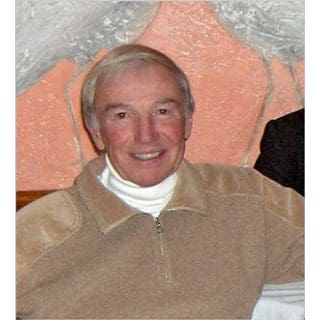 Man smiling in a beige sweater indoors.