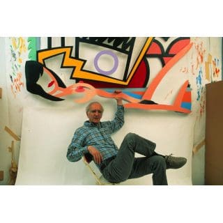 Man sitting under colorful abstract artwork.