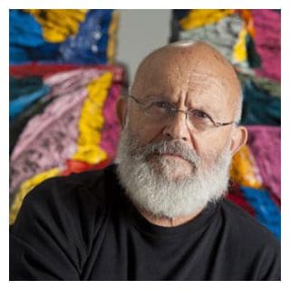 Man with beard in front of colorful art.