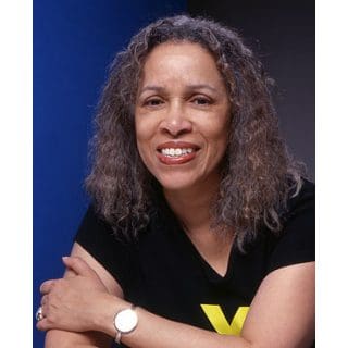 Smiling woman with curly hair, blue background.