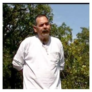 Man in white shirt standing outdoors.