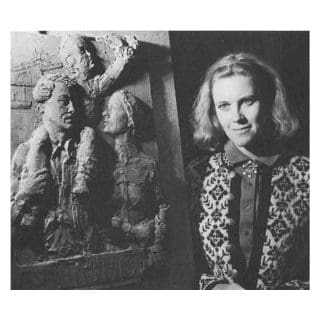 Woman standing beside sculpted relief artwork.