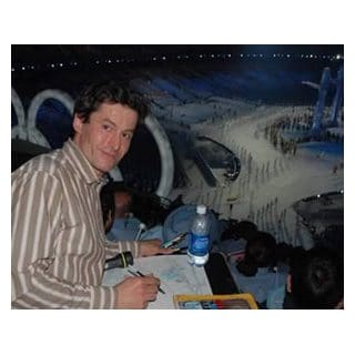 Man seated, overlooking large indoor event.
