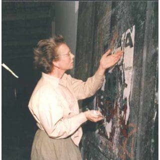 Person examining and restoring an old painting.