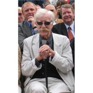 Elderly man in glasses with cane seated.