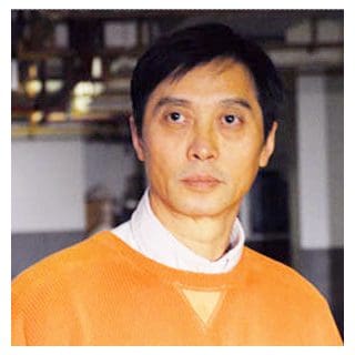 Man wearing orange sweater, looking forward.
