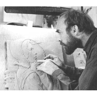 Artist carving a detailed relief sculpture.